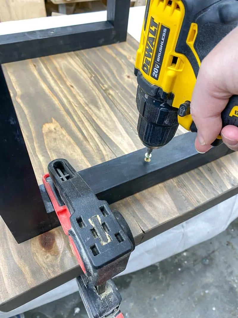 attaching the top of the DIY rustic end table to the legs with screws